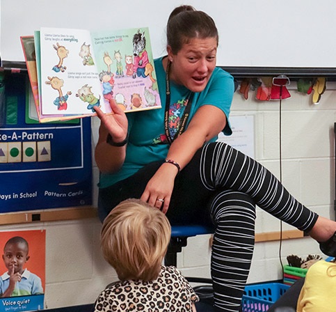Teacher reading to a group of young students